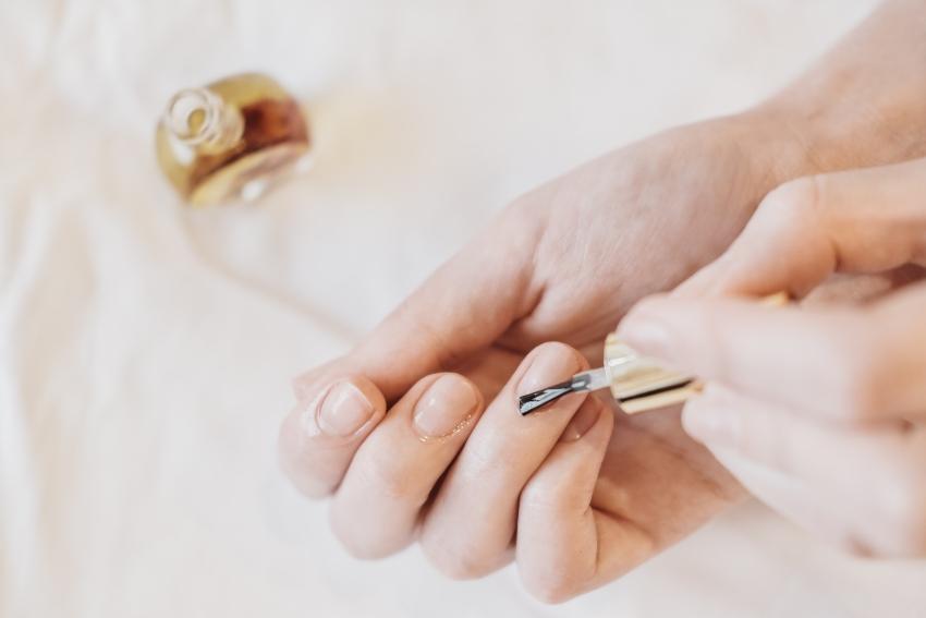 Frau trägt Nagelöl mit einem Pinsel auf