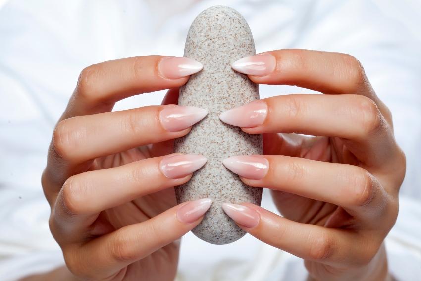 Frau mit Babyboomer Nails hält Stein fest