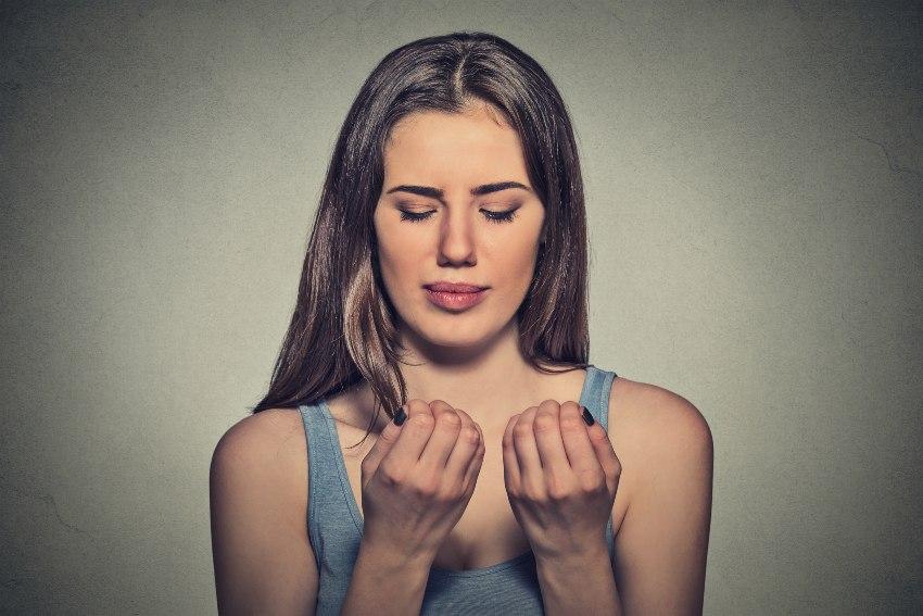 Eine junge Frau betrachtet kritisch ihre Fingernägel 