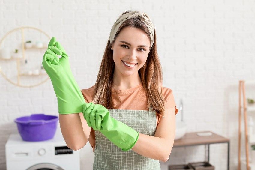 Eine Frau zieht sich einen Gummihandschuh über, um zu putzen