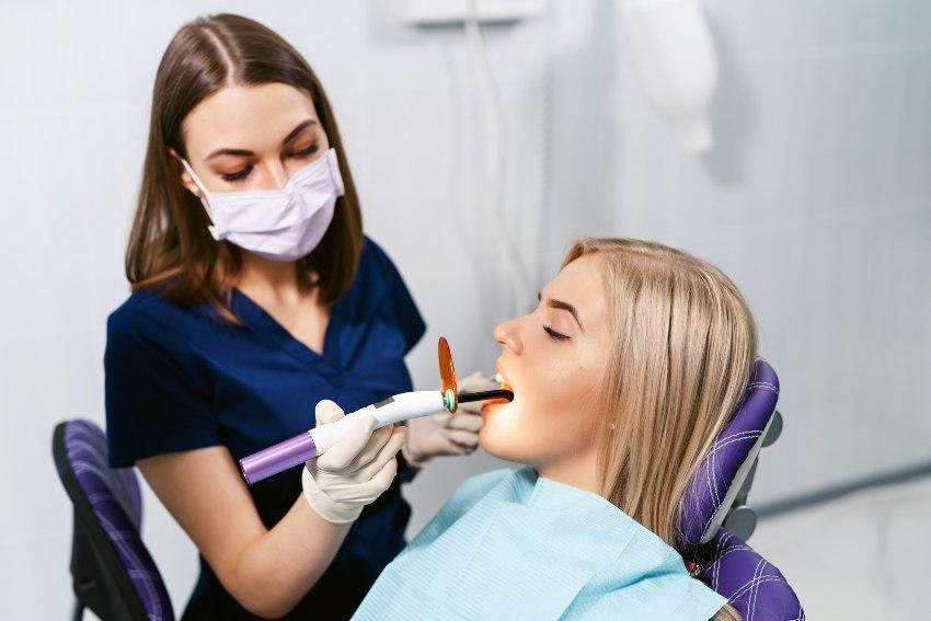 Während einer Zahnbehandlung sorgt die Ärztin mit einer UV-Lampe für das Aushärten der Dispersionsschicht 