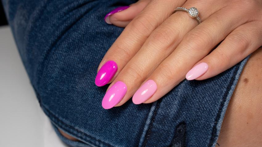 Eine Frau präsentiert ihr Nageldesign in unterschiedlichen Pinktönen