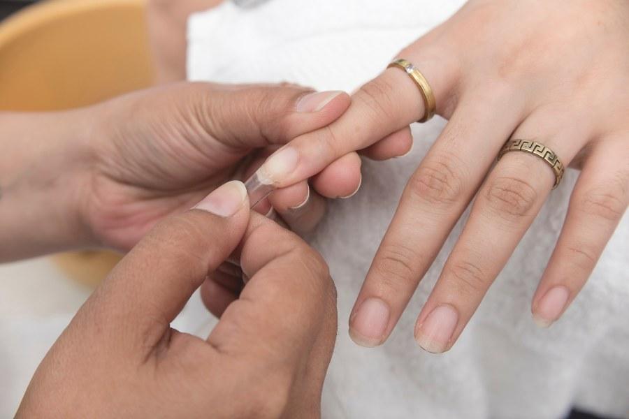 Jemand bringt Nail Tip auf Fingernagel an - Nagelverlängerung mit Tips