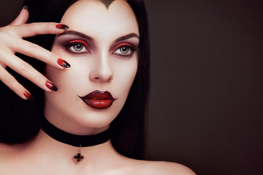 Eine Frau trägt ein Vampir-Kostüm zu Halloween und präsentiert das passende Nageldesign 