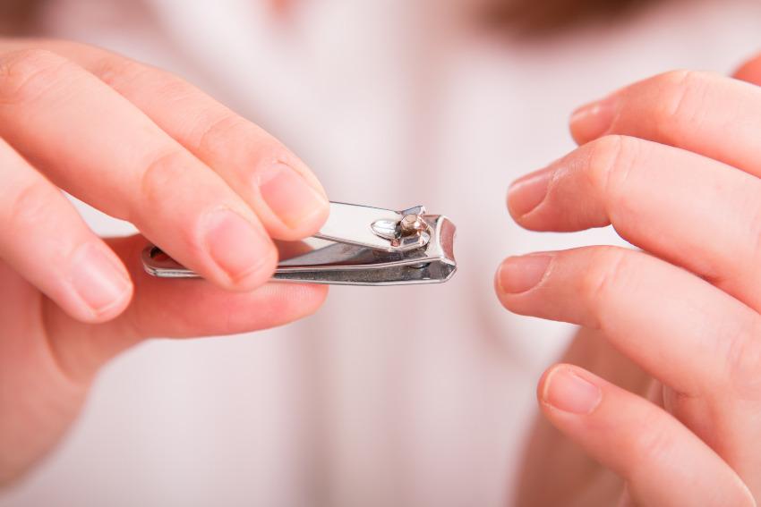 Eine Frau benutzt einen Nagelknipser, um ihre Nägel zu kürzen