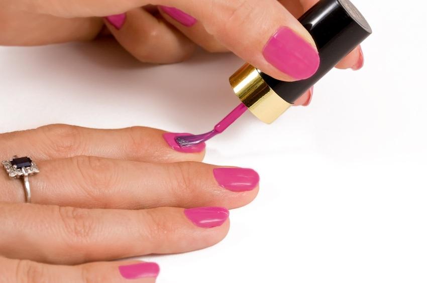 Frau lackiert Fingernaegel mit pinkem Lack - Langanhaltender Nagellack