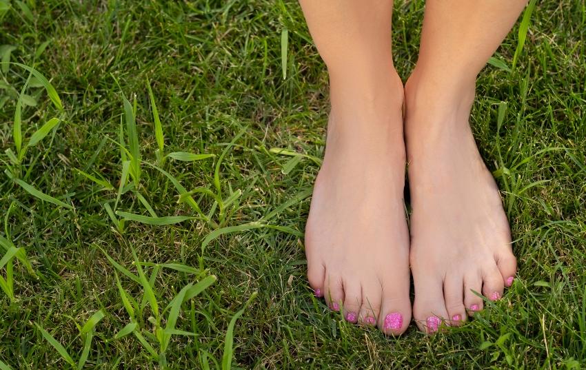 Frauenfüsse-Frau-steht-im-Gras - Barfuß im Sommer