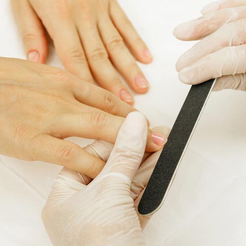 Ein Fingernagel wird mit einer Nagelfeile für die Maniküre vorbereitet