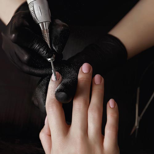 Mit Schleifkappen werden die Fingernägel einer Kundin bei einer Maniküre bearbeitet